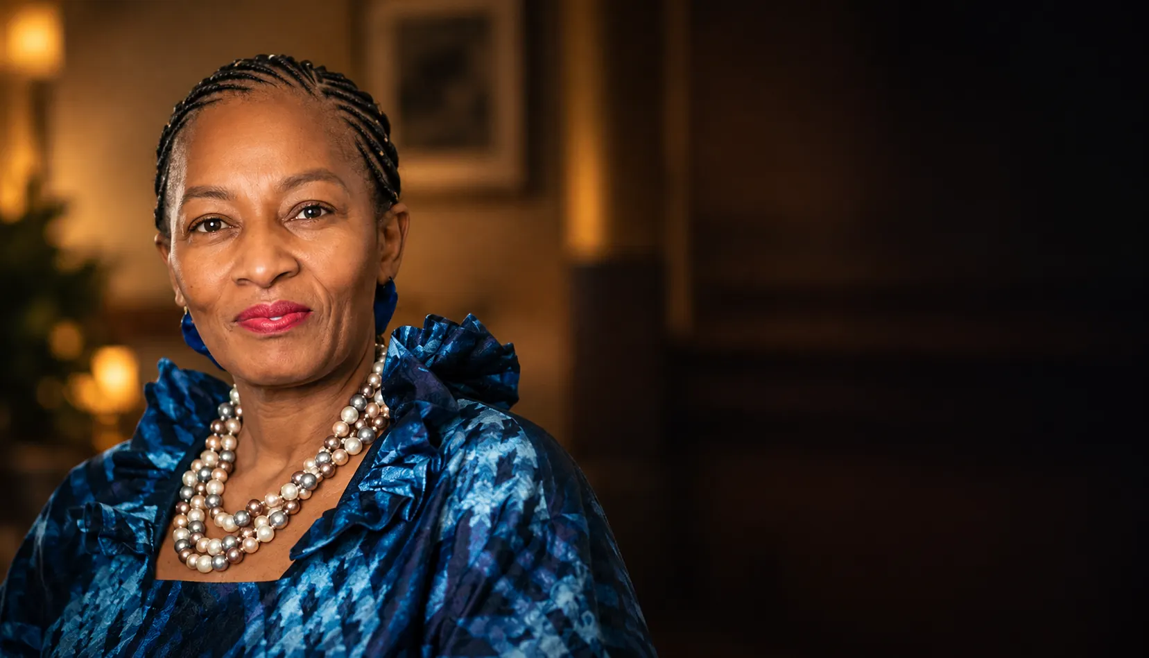 Close portrait of a woman wearing a blue patterned top and a layered pearl necklace
